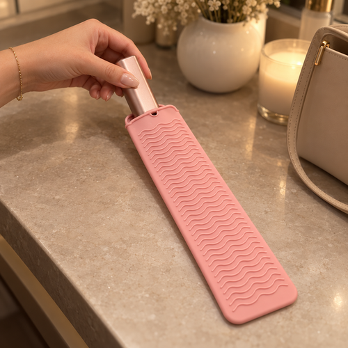 Oaklo™ Heat-Safe Travel Pouch in Blush Pink with the rose Oaklo™ Cordless Bangs Comb sliding in, on a warm vanity